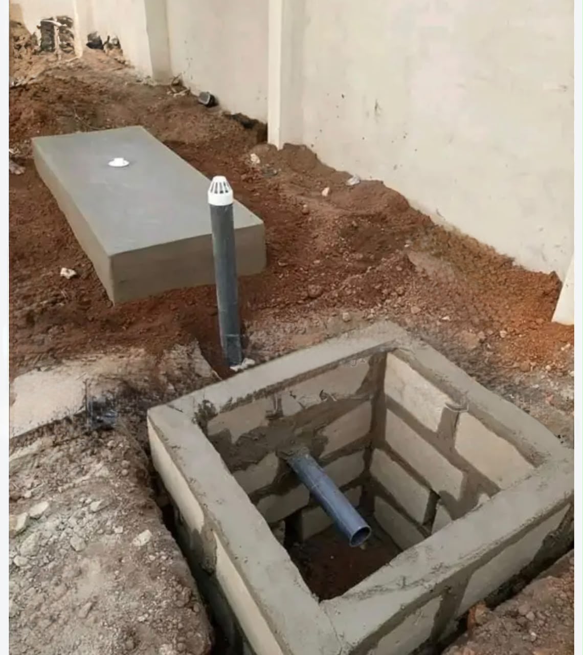 Concrete biodigester tank and blockwork soakaway pit with vent pipe during installation